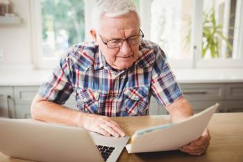 Older male reading while in front of a laptop